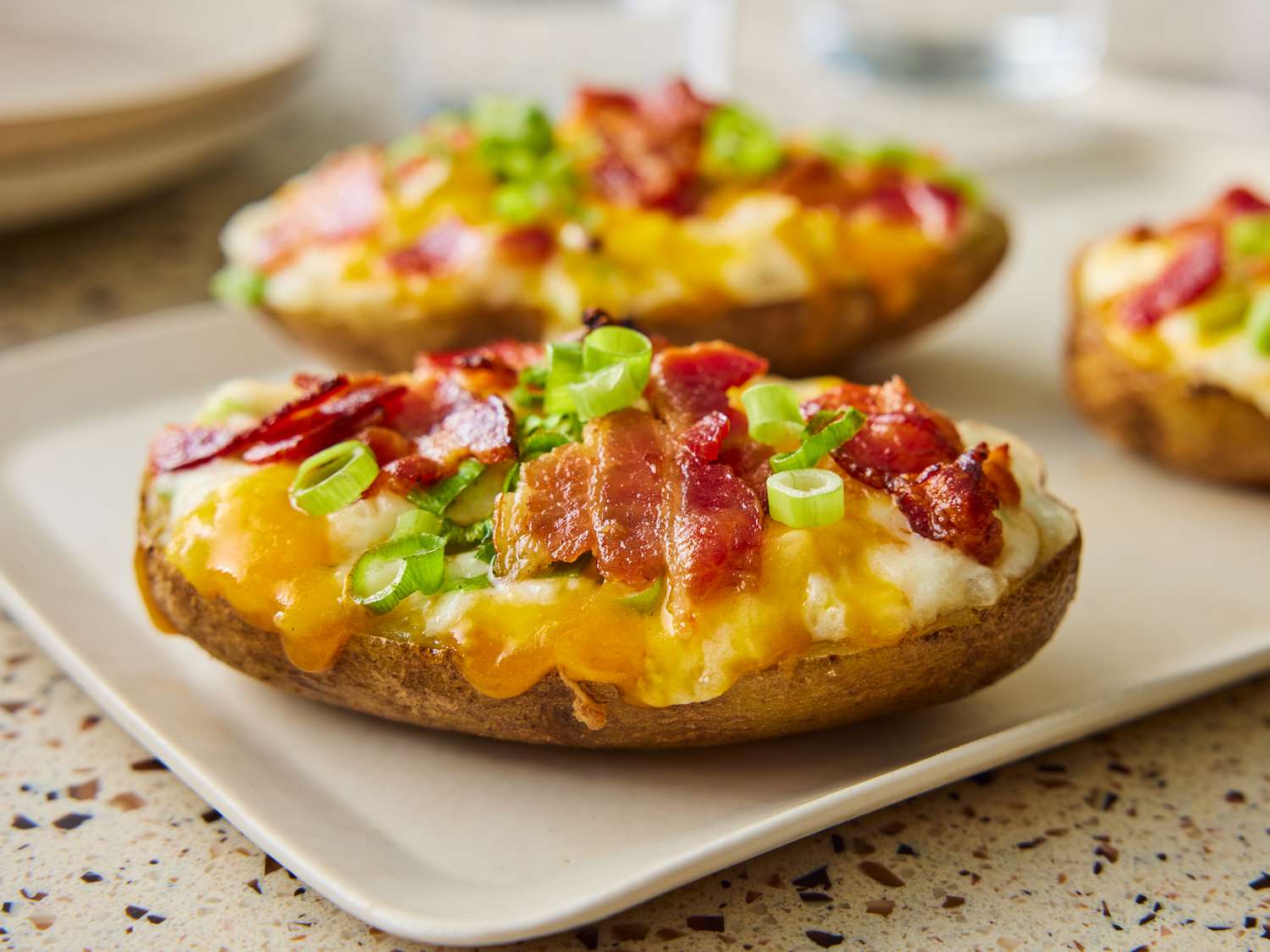 Baked potato dish topped with green onion and bacon.