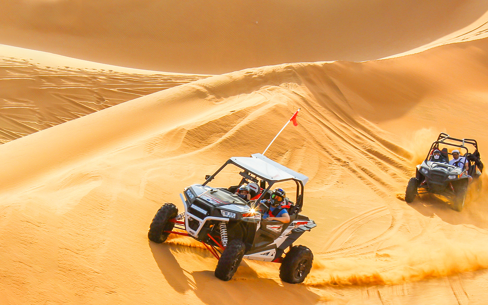 A dune buggy riding rapidly across sand dunes.