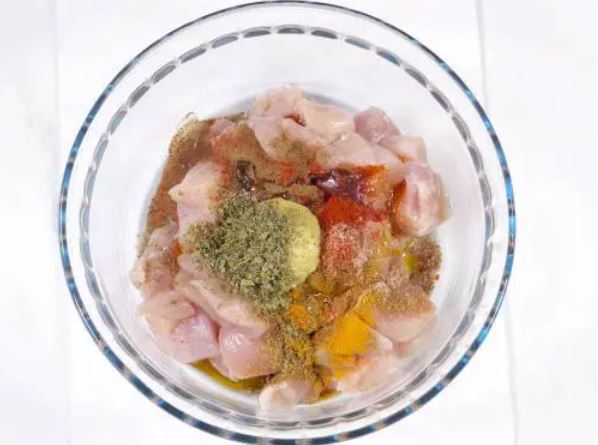 Raw chicken with many spices on it.