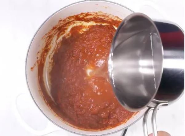 An image of pouring boiling water into the sauce. 